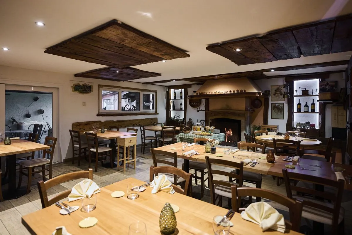 Sala rustica interna con tavoli in legno e travi a vista